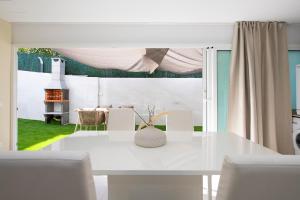a white dining room with a white table and chairs at PLAYA a 3 minutos Parking barbacoa Apartamento en Castelldefels in Castelldefels
