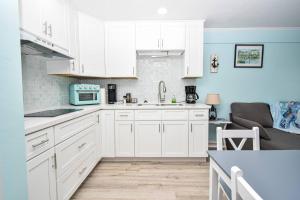a kitchen with white cabinets and a blue wall at Cedar Key Island Condo 228 in Cedar Key