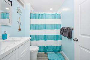 a bathroom with a blue and white shower curtain at Cedar Key Island Condo 228 in Cedar Key +14 photos