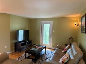 a living room with a couch and a tv at Havre du lac magog in Sainte-Catherine-de-Hatley