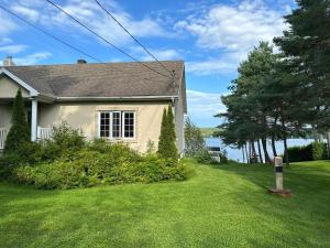 a house with a green yard with a house at Havre du lac magog in Sainte-Catherine-de-Hatley