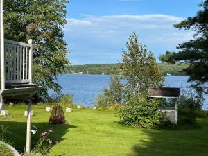 a yard with a bench and a view of the water at Havre du lac magog in Sainte-Catherine-de-Hatley