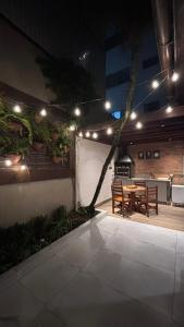 une terrasse avec une table et une salle à manger éclairée dans l'établissement Palais House, à São Vicente