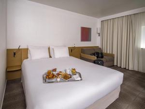 a hotel room with a large bed with a tray of food on it at Novotel Nantes Centre Gare in Nantes