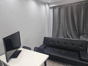 a living room with a couch and a desk with a television at Penge lovely studio in Sydenham