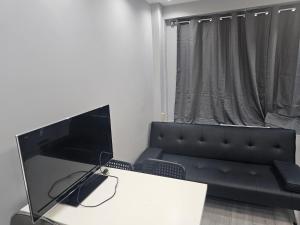 a living room with a black couch and a television at Penge lovely studio in Sydenham +7 photos