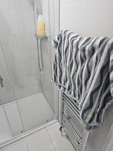 a shower with a black and white towel on a towel rack at Penge lovely studio in Sydenham