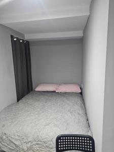 a small bedroom with a bed with pink pillows at Penge lovely studio in Sydenham
