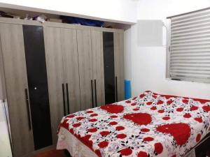 - une chambre dotée d'un lit avec une couverture rouge et blanche dans l'établissement Casa Pé na Areia Centro de Mongaguá, à Mongaguá