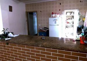 Il comprend une cuisine équipée d'un comptoir et d'un réfrigérateur blanc. dans l'établissement Casa Pé na Areia Centro de Mongaguá, à Mongaguá