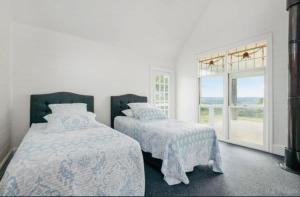 Una habitación blanca con dos camas y una ventana. en French Island Hill House, 