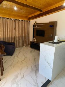 a living room with a white marble floor and a television at Kitnet Centro da Cidade in São Bento do Sapucaí