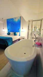 ein Badezimmer mit einer Badewanne und ein Schlafzimmer mit einem Bett in der Unterkunft Bhanwar Pattaya Park Hotel in Pattaya South