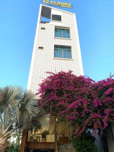 ein hohes Gebäude mit lila Blumen davor in der Unterkunft Cloud7 hotel in Phu Quoc
