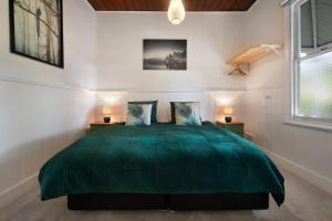 a bedroom with a green bed with two lamps at Wayward Cottage in Daylesford