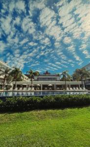a building with palm trees and a cloudy sky at Refúgio VIP Pé na Areia no Campeche - Piscina, Sauna e Academia até 08 pessoas in Florianópolis