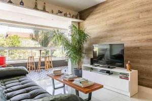 a living room with a couch and a tv at Refúgio VIP Pé na Areia no Campeche - Piscina, Sauna e Academia até 08 pessoas in Florianópolis