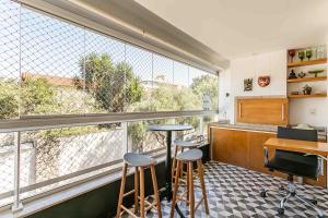a bar with two stools in a room with large windows at Refúgio VIP Pé na Areia no Campeche - Piscina, Sauna e Academia até 08 pessoas in Florianópolis