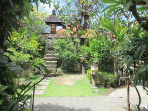 un jardín con una torre de piedra con escaleras y un edificio en Mona Homestay, en Sanur