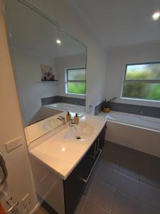 a bathroom with a sink and a large mirror at Enjoy 4br home with lots of comfort & convenience in Taupo