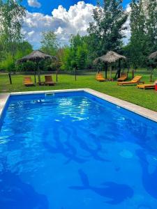 ein großer blauer Pool im Hof mit Sonnenschirmen in der Unterkunft Villa Marta Casa de Campo in San Lorenzo