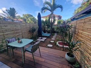 eine Terrasse mit Tisch und Stühlen auf einem Holzdeck in der Unterkunft Studio Selva in Cayenne