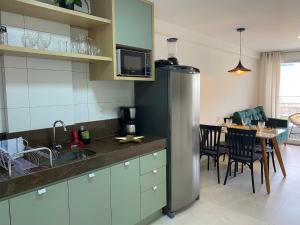 a kitchen with a stainless steel refrigerator and a table at Bela Hospedagem - Puerto Ventura, frente mar e ao lado do food park in João Pessoa