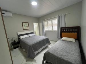 ein Schlafzimmer mit zwei Betten und einem Fenster in der Unterkunft Residencial Elsa Tarcila in Bombinhas