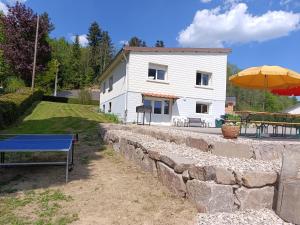 ein Haus mit einer Steinmauer, einem Tisch und einem Sonnenschirm in der Unterkunft Séjour détente en campagne avec spa et activités famille - FR-1-589-757 in Fraize
