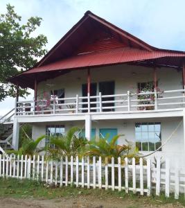 a white house with a white picket fence at Apart Cabaña KTIK in San Bernardo del Viento