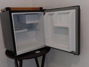 an empty refrigerator with its door open on a stool at Sana Suítes in Macaé