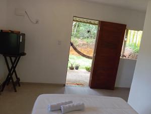 a room with a bed and a door to a yard at Sana Suítes in Macaé