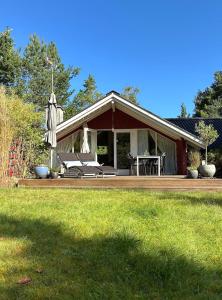 uma casa com um deck com um guarda-chuva no quintal em Family Cabin By The Calm Waters Of Limfjord em Højslev
