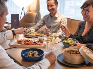 eine Gruppe von Menschen sitzt um einen Tisch herum und isst in der Unterkunft Novotel Suites Paris CDG Airport Villepinte in Roissy-en-France