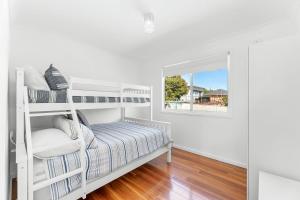a white bedroom with a bunk bed and a window at Kianga Lodge, 1 Sunset Blvd in Kianga