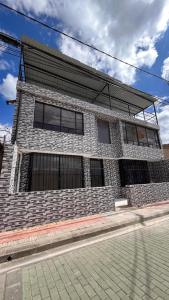 un bâtiment en briques avec des fenêtres donnant sur une rue dans l'établissement Hostal Dulcinea, à Tocancipá