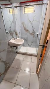 une salle de bain avec un lavabo et une douche en verre dans l'établissement Hostal Dulcinea, à Tocancipá