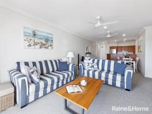 a living room with two couches and a table at Villa 7 - The Breakers Resort in Yamba