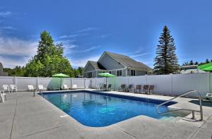 a swimming pool with chairs and umbrellas next to a fence at Killington Center Renovated Studio with Kitchenette on Bus Route and Discounted Ski Rentals in The Woods