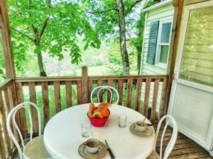 a white table with a basket of fruit on a porch at Mobil home 24m² avec terrasse à Beaumont-du-Périgord - API-1-52-412 in Beaumont-du-Périgord