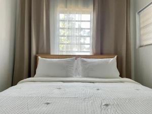 ein Bett mit weißer Bettwäsche und einem Fenster in der Unterkunft Abigail's Sunlit Nook in Tortola Island