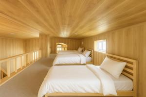 Duas camas num quarto com tecto em madeira em ペンションハートウォーマー em Wada