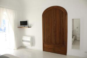 ein Zimmer mit einem Holzschrank und einem Fernseher in der Unterkunft La Positanella - Positano bright apartment in Positano