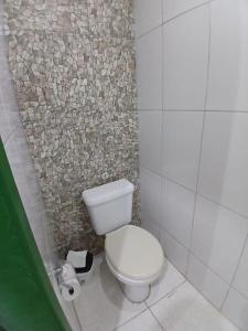 ein Badezimmer mit Toilette und Steinwand in der Unterkunft happy sigull in Arraial do Cabo