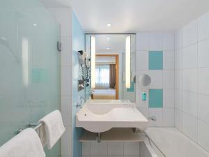 a bathroom with a sink and a shower and a mirror at Novotel Aachen City in Aachen +98 photos