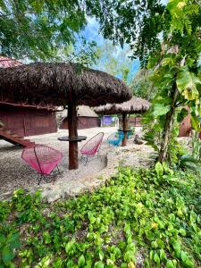 a group of chairs and a table and a straw hut at Cabañas Bacali in Bacalar