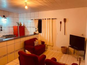 a living room with a red chair and a tv at Casa Guiné in Goiás