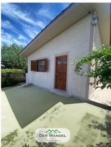 une petite maison blanche avec une porte marron dans l'établissement Casa Der Wandel, à Villa General Belgrano
