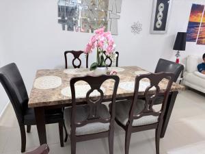 a dining room table with black chairs and pink flowers at Apartamentos en Pablo mellas morales 3ra etapa M-R42 Apt 101 Santo Domingo in Hato Nuevo +9 photos