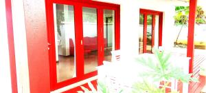 une porte rouge sur une maison avec une plante dans l'établissement Doomsday Ark Ltd, à Port Vila 1 autre photo